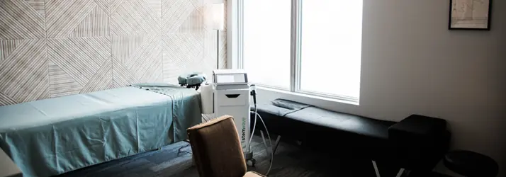StemWave treatment room with a padded table, chair, large windows, and therapy equipment